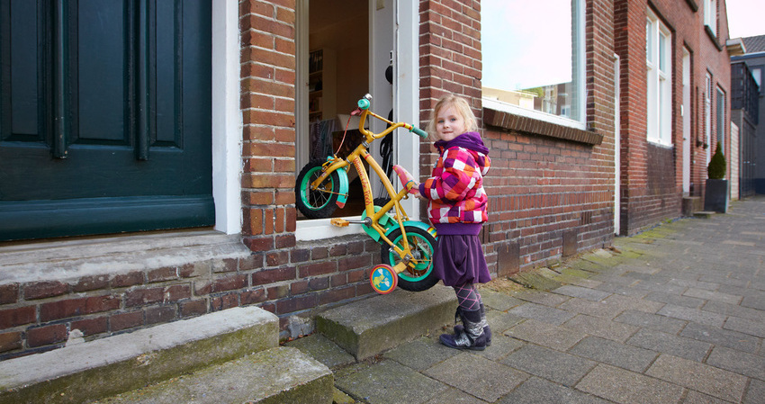Foto van meisje met fietsje bij voordeur